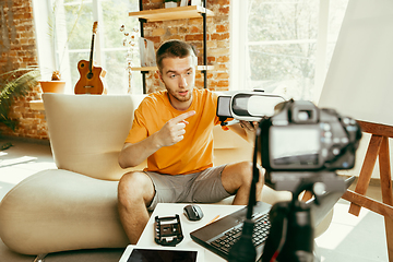 Image showing Caucasian male blogger with camera recording video review of gadgets at home