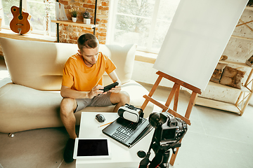 Image showing Caucasian male blogger with camera recording video review of gadgets at home