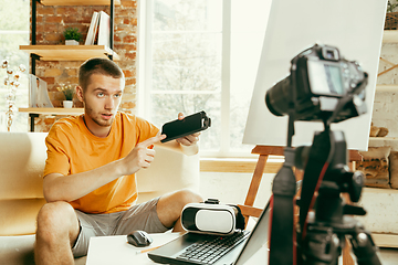 Image showing Caucasian male blogger with camera recording video review of gadgets at home