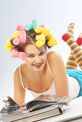 Image showing A woman with hair curlers and magazines