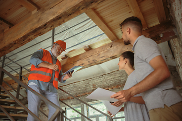 Image showing Foreman or achitect shows house, office or store design plans to a young couple