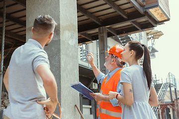 Image showing Foreman or achitect shows house, office or store design plans to a young couple