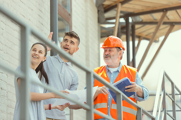 Image showing Foreman or achitect shows house, office or store design plans to a young couple