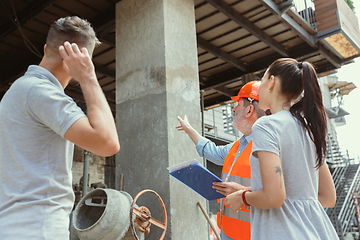 Image showing Foreman or achitect shows house, office or store design plans to a young couple