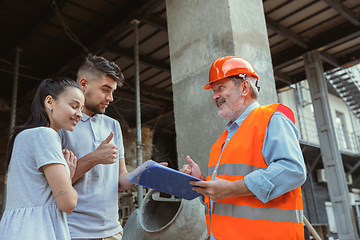 Image showing Foreman or achitect shows house, office or store design plans to a young couple