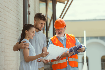 Image showing Foreman or achitect shows house, office or store design plans to a young couple