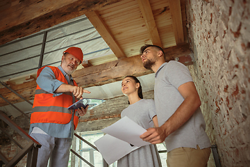 Image showing Foreman or achitect shows house, office or store design plans to a young couple