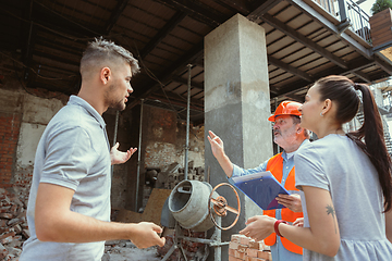 Image showing Foreman or achitect shows house, office or store design plans to a young couple