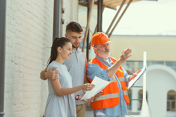 Image showing Foreman or achitect shows house, office or store design plans to a young couple