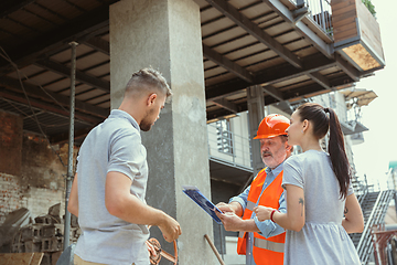 Image showing Foreman or achitect shows house, office or store design plans to a young couple