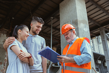 Image showing Foreman or achitect shows house, office or store design plans to a young couple