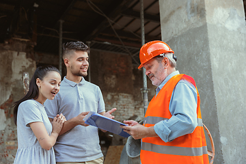 Image showing Foreman or achitect shows house, office or store design plans to a young couple