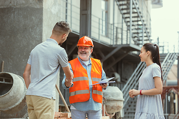 Image showing Foreman or achitect shows house, office or store design plans to a young couple