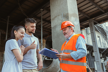 Image showing Foreman or achitect shows house, office or store design plans to a young couple