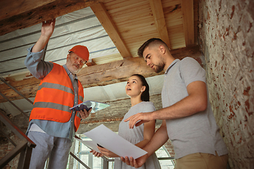 Image showing Foreman or achitect shows house, office or store design plans to a young couple