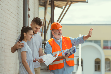 Image showing Foreman or achitect shows house, office or store design plans to a young couple