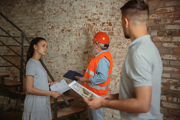 Image showing Foreman or achitect shows house, office or store design plans to a young couple