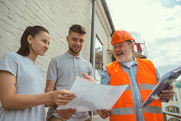 Image showing Foreman or achitect shows house, office or store design plans to a young couple