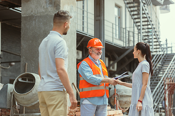 Image showing Foreman or achitect shows house, office or store design plans to a young couple