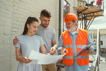 Image showing Foreman or achitect shows house, office or store design plans to a young couple