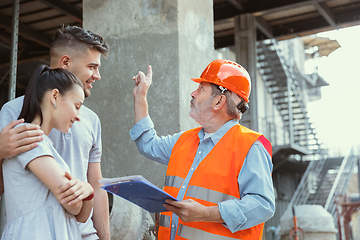 Image showing Foreman or achitect shows house, office or store design plans to a young couple