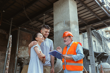 Image showing Foreman or achitect shows house, office or store design plans to a young couple