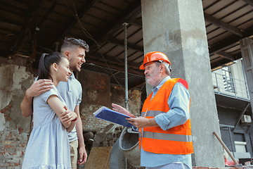 Image showing Foreman or achitect shows house, office or store design plans to a young couple