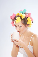 Image showing A woman in hair curlers with a cup