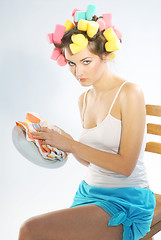 Image showing A woman in hair curlers is drying up the plate