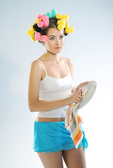 Image showing A woman in hair curlers is drying up the plate