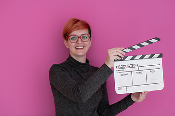 Image showing redhead woman holding movie  clapper on pink background