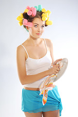 Image showing A woman in hair curlers is drying up the plate