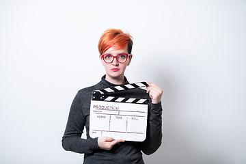 Image showing redhead woman holding movie  clapper on white background