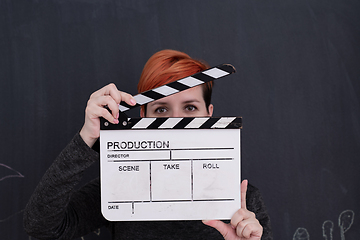 Image showing redhead woman holding clapper on black background