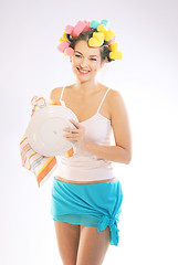 Image showing A woman in hair curlers is drying up the plate