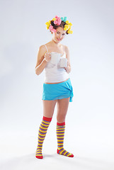 Image showing A woman in hair curlers with a teapot and cup