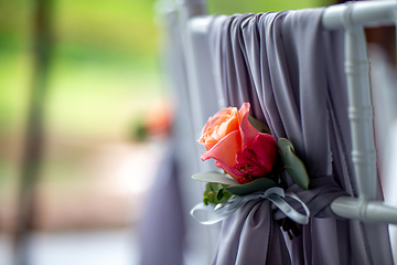Image showing Pink rose tied on the chair 
