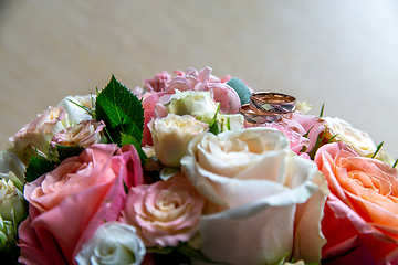 Image showing Bouquet of bride with roses and gold wedding rings.