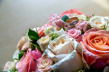 Image showing Bouquet of bride with roses and gold wedding rings.