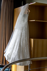 Image showing Bridal dress hanging at wooden closet