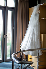 Image showing Bridal dress hanging at wooden closet