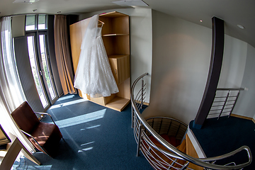 Image showing Bridal dress hanging at wooden closet