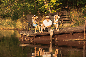 Image showing Cute little girls and their granddad are on fishing at the lake or river