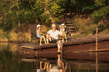 Image showing Cute little girls and their granddad are on fishing at the lake or river