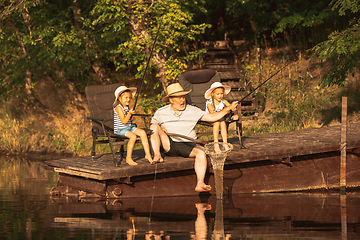 Image showing Cute little girls and their granddad are on fishing at the lake or river