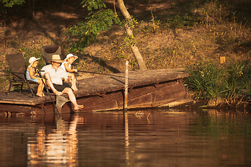 Image showing Cute little girls and their granddad are on fishing at the lake or river