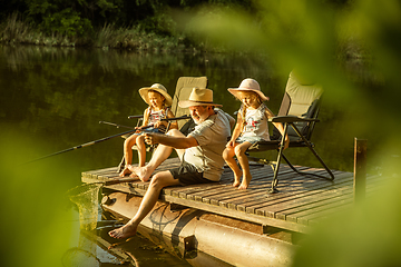 Image showing Cute little girls and their granddad are on fishing at the lake or river