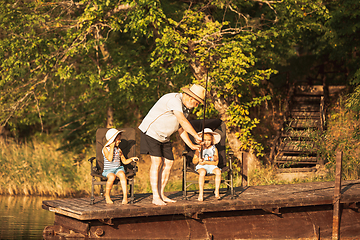 Image showing Cute little girls and their granddad are on fishing at the lake or river