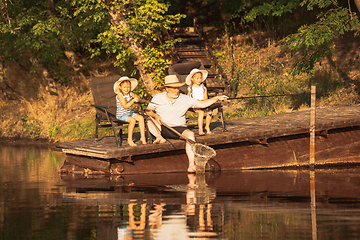 Image showing Cute little girls and their granddad are on fishing at the lake or river