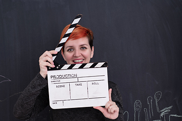 Image showing redhead woman holding clapper on black background